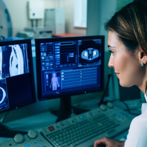 Female radiologist with long brown hair reviewing a PET scan on a computer